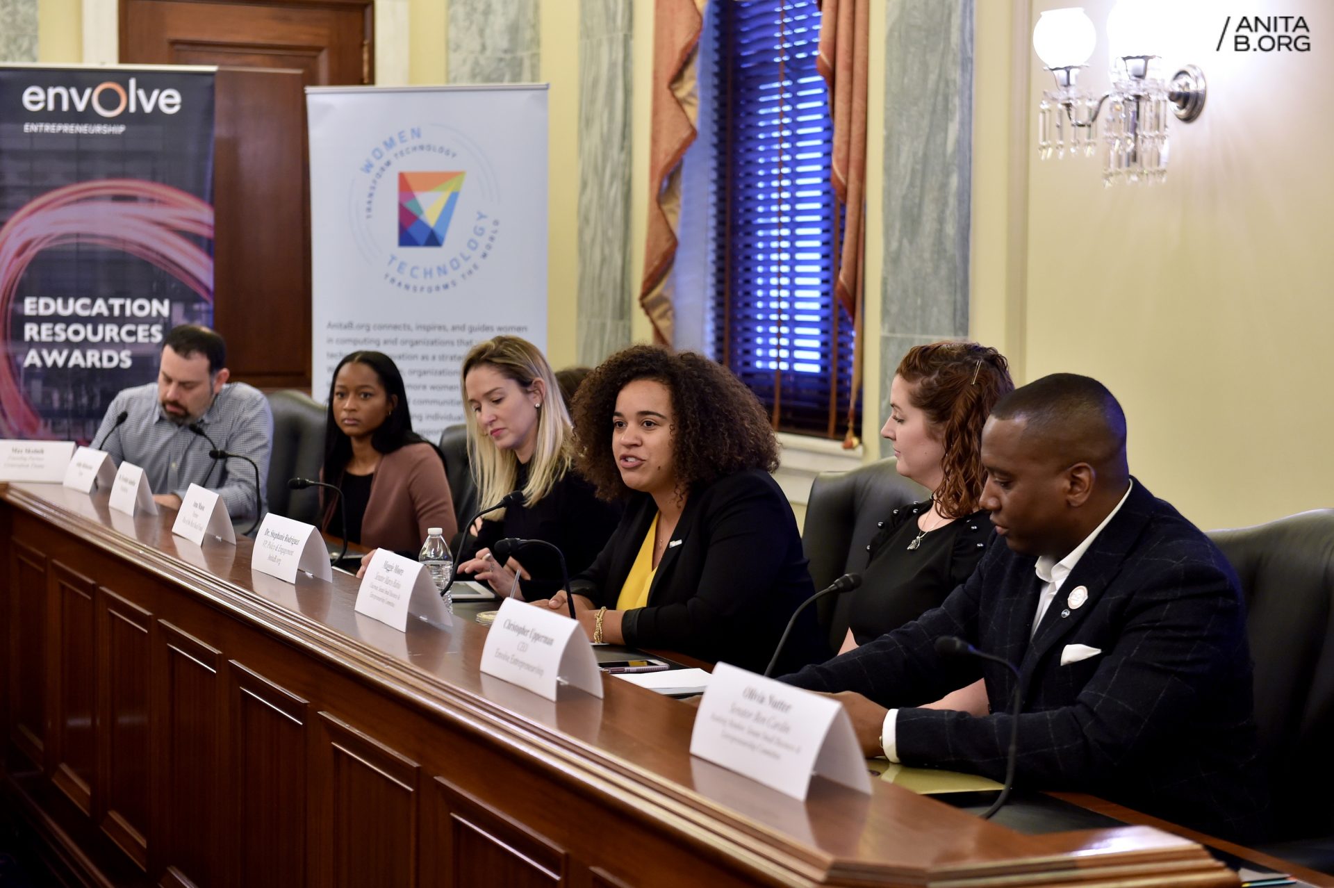 5 people seated at a judicial style desk with an AnitaB.org banner in the background.